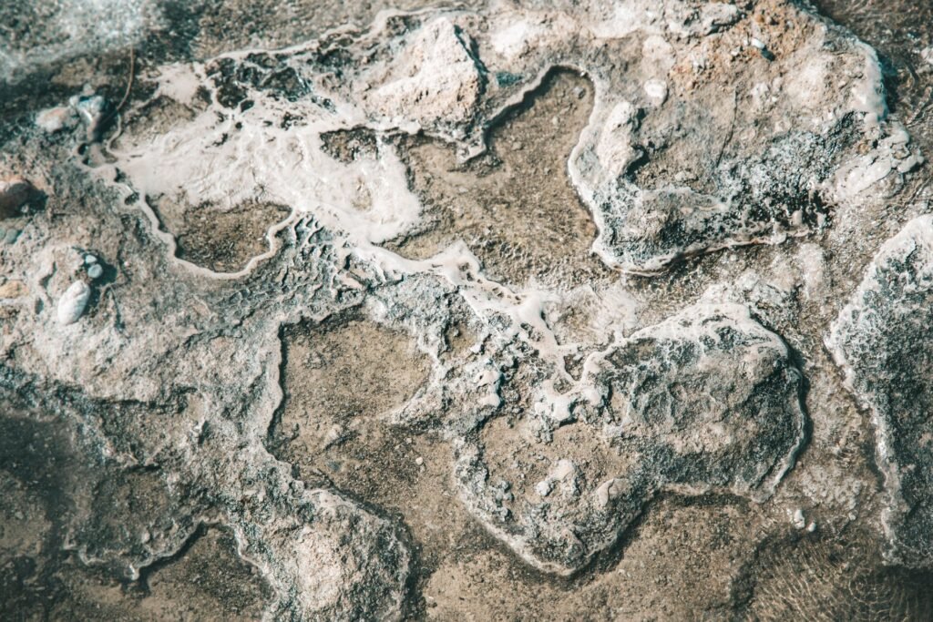 White calcium crust spread across wet rock, the same deposit a salt free water conditioner is sold to prevent