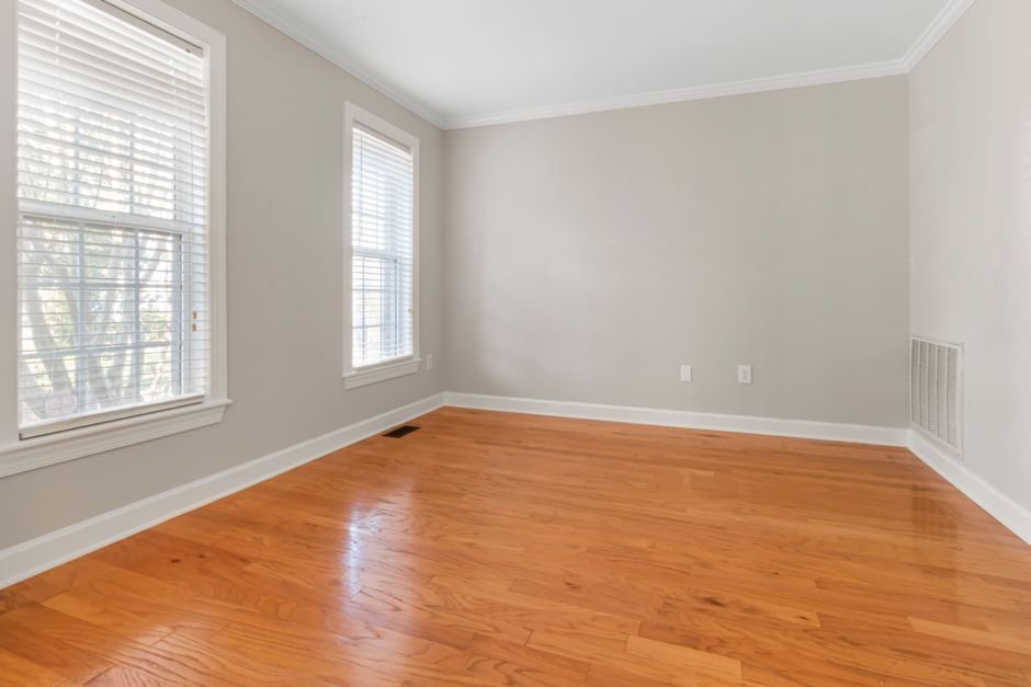 An empty room with a polished hardwood floor and pale walls, the kind of finished surface a washing machine drain pan is fitted to protect